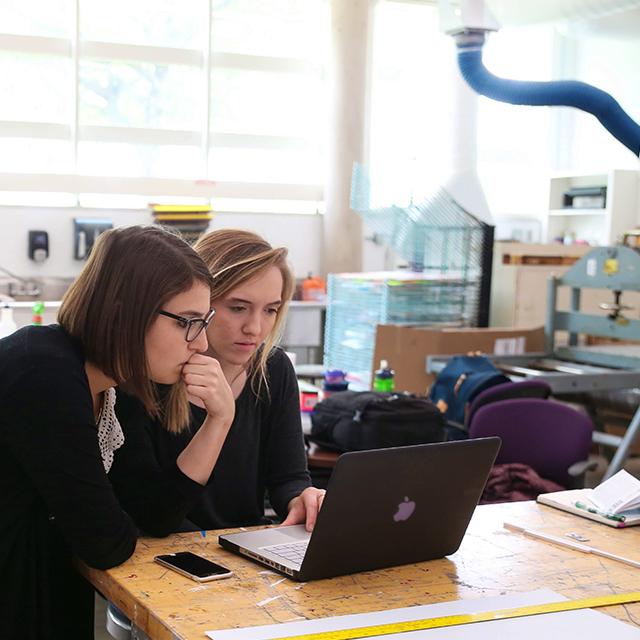 两名TCU女学生在版画工作室查看笔记本电脑